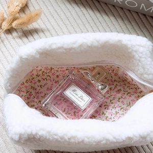 Nahaufnahme der cremefarbenen Lammwolle-Kosmetiktasche mit rosa Blumenfutter