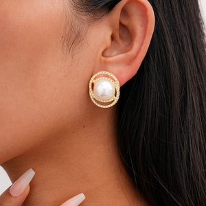 Close-up of elegant gold plated pearl stud earrings with sparkling zircon halo on model