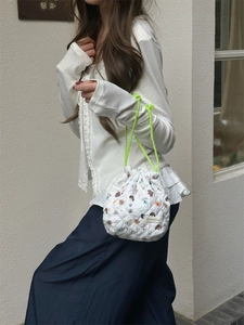 Quilted cartoon storage bag with neon green drawstring handle shown in hand