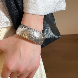 Détail d'un large bracelet manchette en argent mat avec relief floral et texture vintage