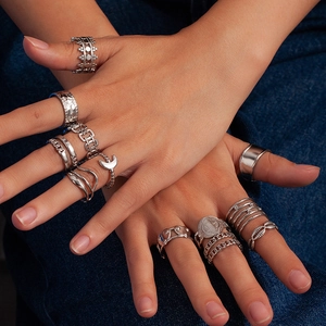 Detail of vintage layered stainless steel rings with moon and crown designs on denim