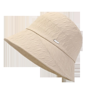 Close-up of beige sun hat featuring 3D geometric texture and silver logo badge detail