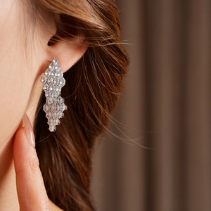 Close-up of elegant silver drop earrings with zircons on model for luxury style