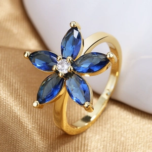 Macro shot of gold flower ring with blue marquise stones and central white zircon detail