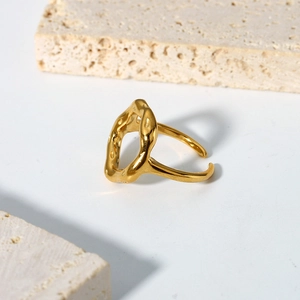 Irregular textured gold plated stainless steel open ring on beige travertine stone