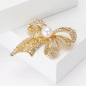 Macro shot of gold bow brooch with sparkling crystals and a large pearl center piece