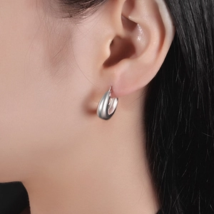 Close-up of polished silver teardrop earrings on model showing glossy mirror finish