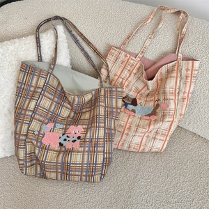 Detail view of plaid tote bags with cute animal embroidery on soft cream sofa