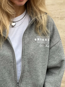 Detail view of the Brooklyn New York print on a grey zip-up hoodie sweater for women