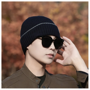 Detail shot of navy knit beanie with gray stripe on a blurred autumn leaf background