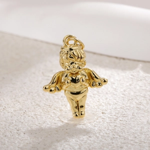 Macro detail of a gold-plated Cupid angel pendant with heart and intricate wing details