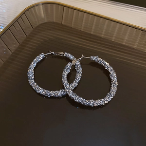 Macro shot of silver U-shaped hoop earrings with shimmering pavé crystal texture