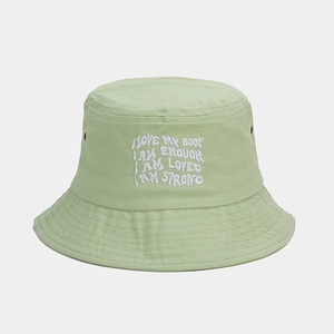 Detail of light green cotton bucket hat with white embroidery and breathable metal eyelets