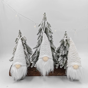 Three Nordic Christmas gnomes with knitted hats and white beards on a wooden base