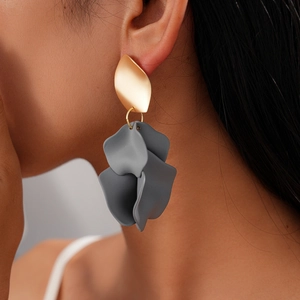 Detailed close-up of a model wearing grey matte acrylic petal earrings with gold leaf studs