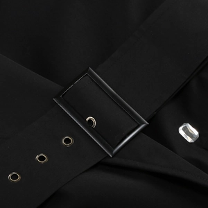Détail d'une robe noire avec large ceinture à oeillets dorés et décor de strass