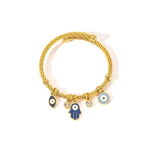 Detail of twisted cable gold bracelet with blue evil eye and hamsa hand charms