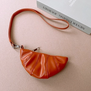 Close-up of caramel faux leather croissant mini necklace pouch with silver metal zipper