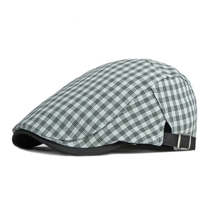 Détail de la boucle métallique réglable et de la sangle noire sur un béret à carreaux