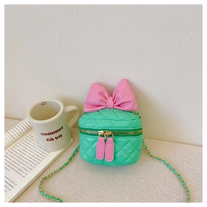 Detail of green quilted mini bag featuring a large pink bow and woven metal chain strap