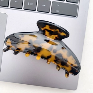 Close-up of tortoise shell pattern acetate hair claw clip resting on a silver laptop keyboard