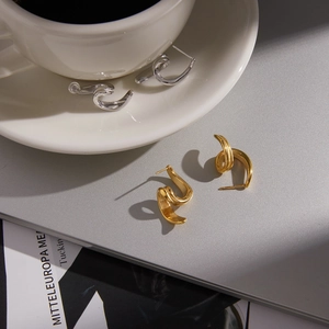 Macro detail of spiral twisted hoop earrings in polished gold and silver finishes