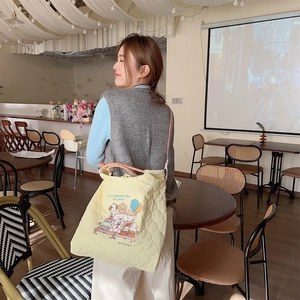 Detail of yellow quilted tote bag with cute dog illustration and soft texture
