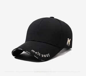 Detail of embroidered M letter and beige text on black cotton baseball cap