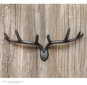 Detail of vintage cast iron antler wall hook mounted on rustic vertical wood texture