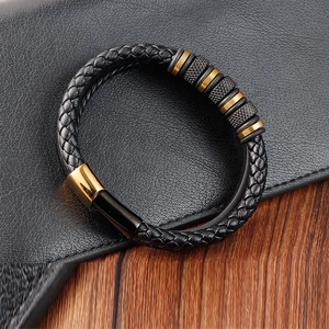 Detailed view of black braided leather bracelet with gold and black decorative metal rings