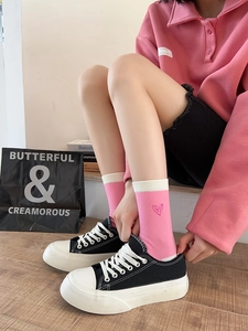 Close-up of pink striped cotton sock featuring a cute red heart embroidery on the side