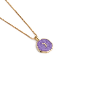 Macro detail of golden moon pendant with purple enamel inlay on a box chain necklace