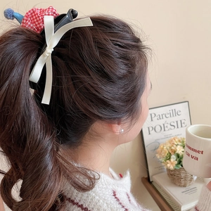 Detail view of red gingham banana hair clip with a white ribbon bow on a brunette ponytail