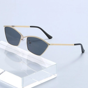 Close-up of gold cat-eye metal sunglasses with grey lenses on a geometric display
