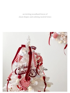 Close-up of white mini Christmas tree with red ribbons and festive candy ornaments