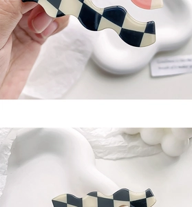 Close-up of wavy checkerboard hair clip in pink and black patterns with glossy finish