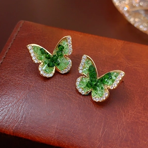Macro shot of gold butterfly earrings featuring green and clear faceted crystals