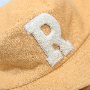 Orange terry cloth bucket hat featuring a white fuzzy letter R patch detail