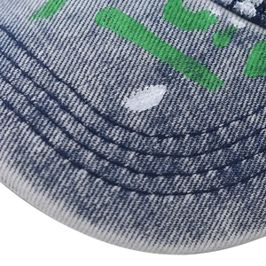 Macro view of washed denim baseball cap brim with graffiti print and detailed stitching