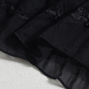 Close-up of black textured fabric with detailed lace trim and ruffled hemline accents