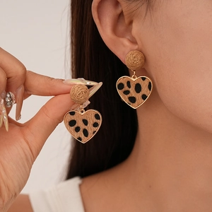 Detailed close-up of leopard print heart earrings with woven ball and golden frame