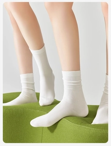 Detail showing high-quality white cotton mid-calf socks worn by a model in a minimal style