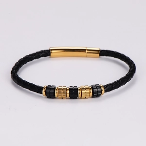 Detalle de pulsera de cuero trenzado negro con cuentas doradas y cierre pulido