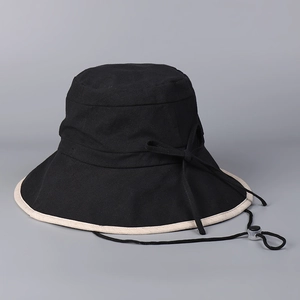 Detail of a black cotton linen sun hat with beige brim trim and adjustable wind rope