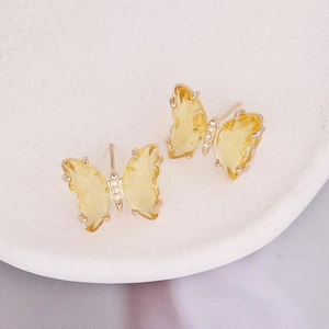 Macro view of butterfly earrings with yellow stones and white zircon on ceramic plate