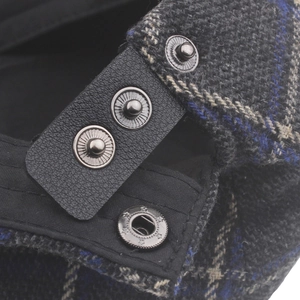 Detail of British plaid beret featuring leather adjustable strap and metal snap button