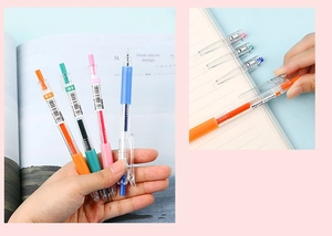Close-up of colorful gel pens with transparent barrels clipped to a journal page