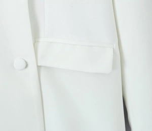 Macro detail of white blazer featuring matching button, stitching, and flap pocket