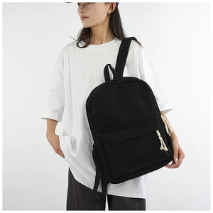 Side view of a black corduroy backpack with white knotted zippers on a female model