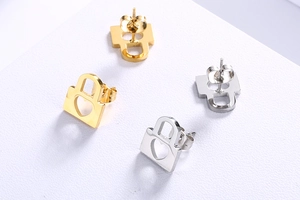 Detail of gold and silver heart-shaped padlock earrings on a white textured surface